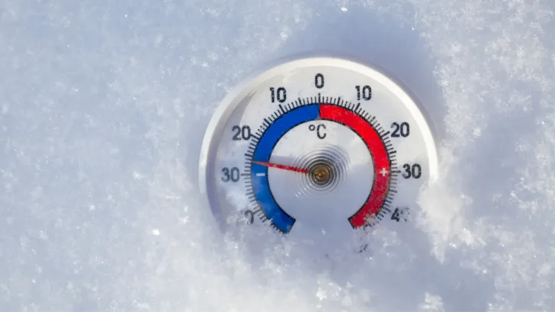 A temperature thermometer laying on some crushed ice 